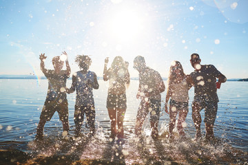 Wall Mural - Group of happy young men and women dancing in water