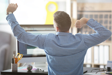 Poster - Young male designer stretching at workplace