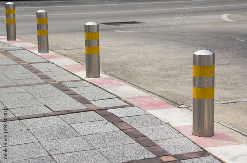 Fotomural Stainless Steel bollards on grey stone pavement