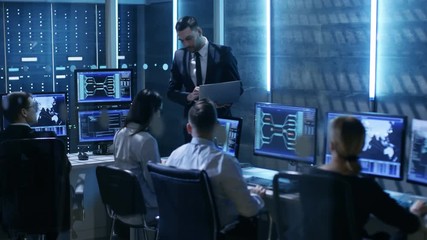 Poster - Professional IT Engineers Working in System Control Center Full of Monitors and Servers. Supervisor Holds Laptop and Holds a Briefing. Possibly Government Agency Conducts Investigation. 