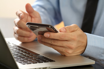 Poster - close up of businessman working with mobile phone and laptop computer on wooden desk in modern office