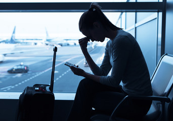 Stressed woman traveler waiting at the airport. Missing flight or getting bad news concept. 