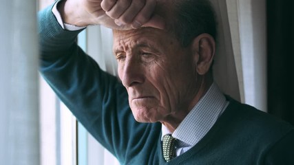 sad thougtful old business man leaning against the window,portrait