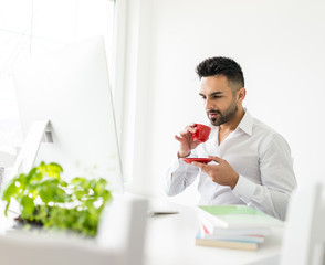 Young confident man working in modern office full of light