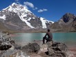 Man sitting by a beautiful shallow emerald and pink lake in the high Andes of Peru on a beautiful blue sky summer day. 