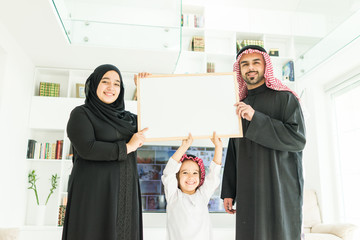 Wall Mural - Happy Arabic Muslim family at modern home having fun and good time together