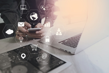 Poster - businessman working with smart phone and laptop computer on wooden desk in modern office with virtual icons interface