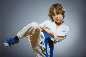 boy in kimono during training karate exercises isolated on gray background