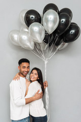 Sticker - Cheerful loving couple standing over grey wall with balloons.