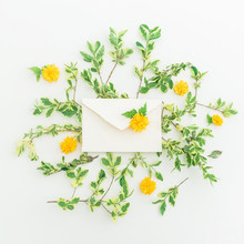 Floral Pattern Branches With Leaves And Yellow Flowers And Paper Envelope On White Background. Flat Lay, Top View. Floral Background.