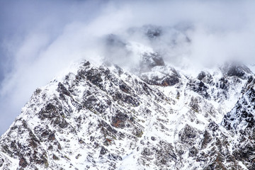 Wall Mural - Beautiful dramatic snowy mountain peaks in clouds. Scenic winter landscape