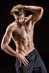 shirtless bearded bodybuilder posing isolated on black in studio