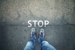 © robsonphoto - Man standing on grunge asphalt city street with written stop sign on the floor, point of view perspective.