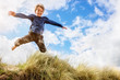 © Brian Jackson - Boy leaping and jumping over sand dunes on beach vacation