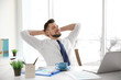 © Africa Studio - Relaxed young man sitting at table in office with hands behind his head