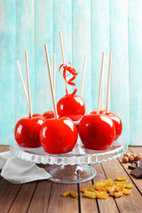 Poster - Delicious toffee apples on glass stand against wooden background