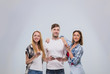 © mast3r - Casual People Group, Young Man Two Woman Happy Smile Using Cell Smart Phone Network Communication Looking To Copy Space Over Grey Background