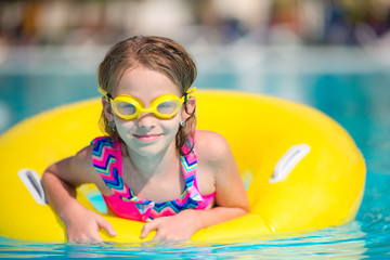 Wall Mural - Little girl with inflatable rubber circle in swimming pool