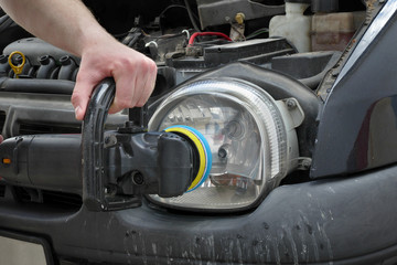 Car light repairing, worker hand with tool polishing headlight