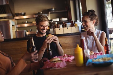 Wall Mural - Happy friends interacting while having meal and beer