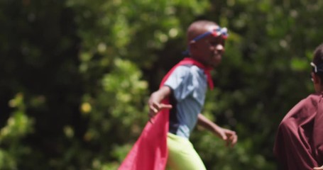 two young children dressed as superheroes chase each other, slow motion