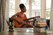 Mixed Race Girl Singing And Playing Classic Guitar At Home