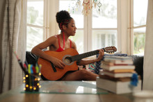 Mixed Race Girl Singing And Playing Classic Guitar At Home