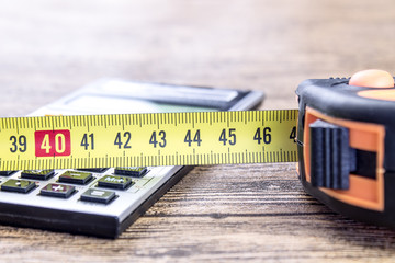 Measure tape meter and calculator on the wooden table