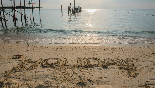 Word “ HOLIDAY “ Write in sand on the beach  .