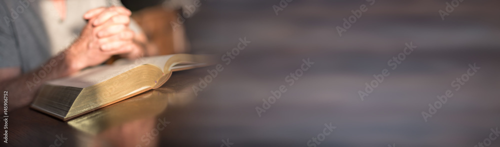 Man praying with his hands over a bible - obrazy, fototapety, plakaty 