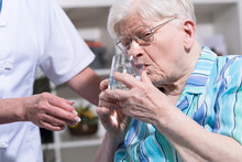 Nurse Giving Glass Of Water To Senior Woman