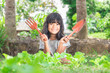 Young girl holding gardening shovel and fork  in vegetable bed