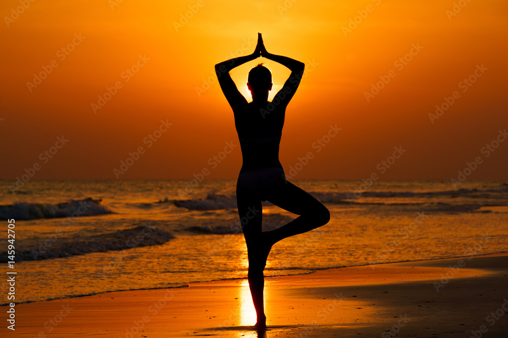 Kobieta ćwicząca jogę na plaży przy zachodzie słońca - obrazy, fototapety, plakaty 