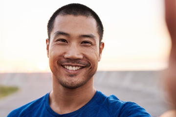 athletic asian man taking a selfie during a morning run