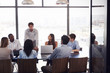 © Monkey Business - Young man stands addressing team at a meeting in a boardroom