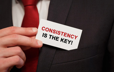 Poster - businessman putting a card with text consistency is the key in the pocket