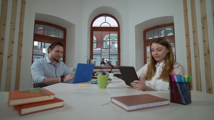 Aufkleber - Partners working together in the office. Co workers sitting at the desk indoors. Caucasian employees using device focused on computer.