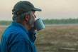 Senior farmer contemplating field with coffee in morning