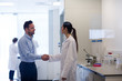© ReeldealHD images - Female scientist shaking hands with pharmaceutical sales rep