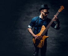Studio Portrait Of The Hipster Bass Player Dressed In Cylinder Hat.