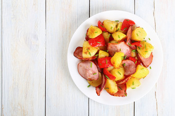 Canvas Print - roasted potato wedges with sausages, top view