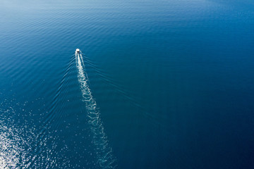 top view of a white boat sailing to the blue sea