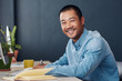 © mavoimages - Smiling young Asian entrepreneur working at his office desk