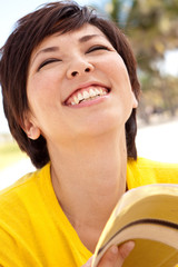 Wall Mural - Asian woman smiling and reading the Bible at the Beach