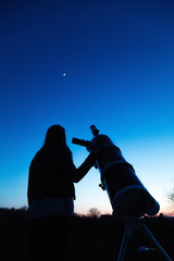 Wall Mural - girl looking at the moon through a telescope.