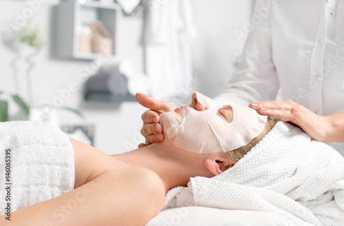 Fotografie, Obraz Beautiful young woman is getting facial mask at spa