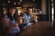 Portrait of happy couple holding glasses of beer at counter