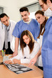 © W PRODUCTION - group of surgeons and medical professional staff discussing on patient radiography outside hospital operating room