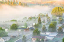 Misty Spring Landscape With Foggy And First Ray Of Early Morning Light. Aerial View Of Small Valley Town At Rural Of Colfax, Eastern Washington, US Surrounded By Morning Fog, Pine Trees And Empty Road