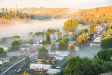 Misty Spring Landscape With Foggy And First Ray Of Early Morning Light. Aerial View Of Small Valley Town At Rural Of Colfax, Eastern Washington, US Surrounded By Morning Fog, Pine Trees And Empty Road